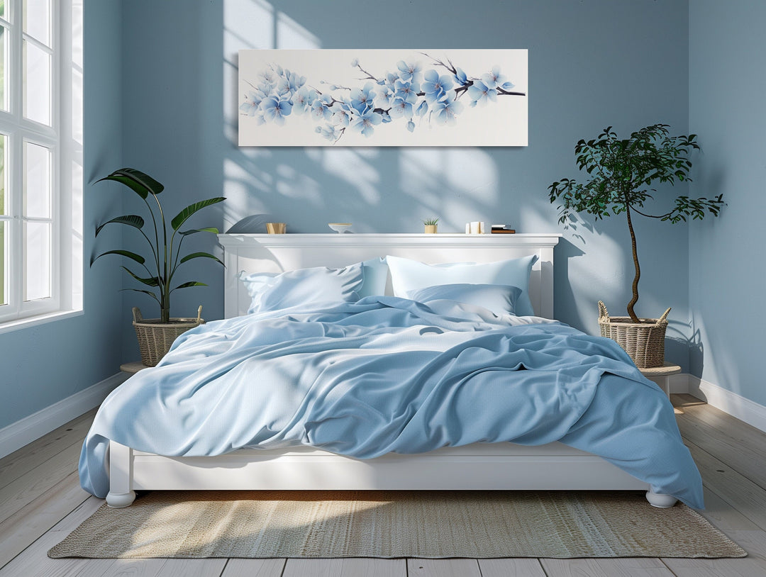 Soft blue blossom flowers long horizontal canvas wall art hanging above a white bed in a blue room.