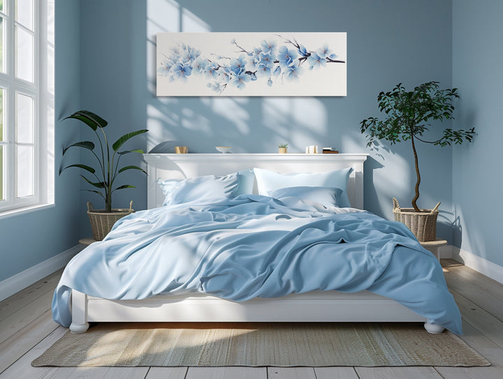 Soft blue blossom flowers long horizontal canvas wall art hanging above a white bed in a blue room.