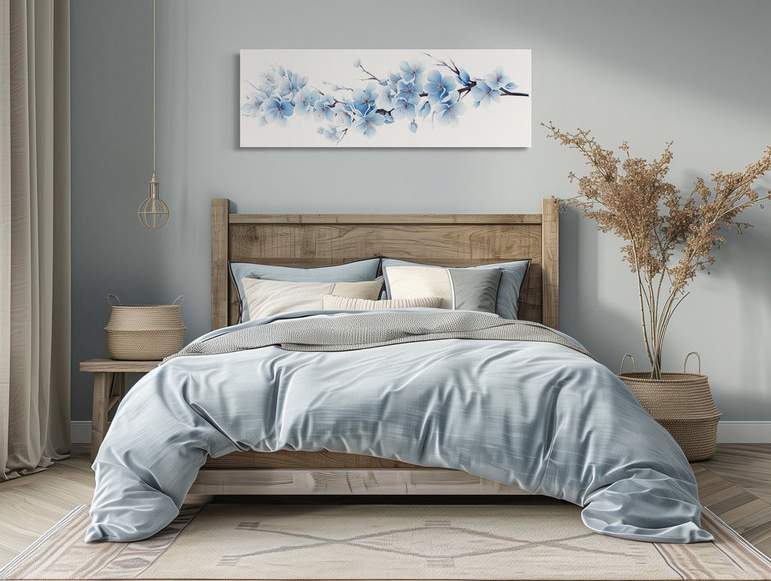 Long horizontal wall art of soft blue blossom flowers hanging above a bed in a serene bedroom.