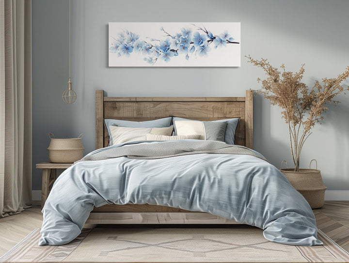 Long horizontal wall art of soft blue blossom flowers hanging above a bed in a serene bedroom.
