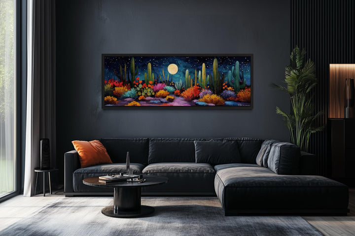 Southwest desert cacti under a moon and starry sky on a long horizontal canvas in a dark room.
