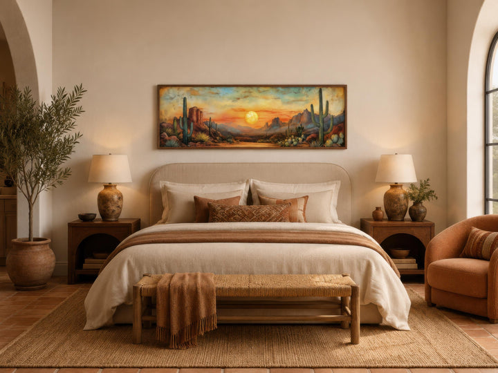 Panoramic Southwestern wall art of a desert sunset with saguaro cacti above a neutral-toned bed.