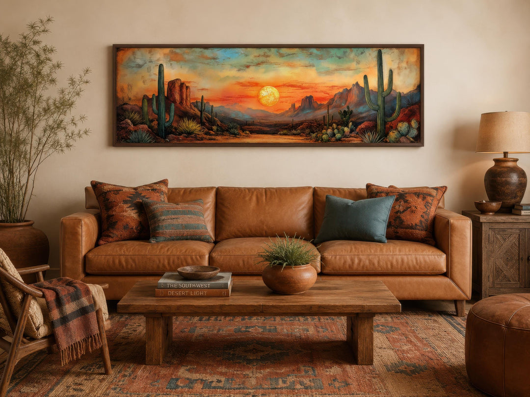 Panoramic Southwestern wall art of a desert sunset with saguaro cacti above a leather sofa.