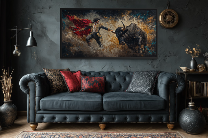Spanish matador fighting a bull canvas wall art displayed above a dark blue tufted sofa.