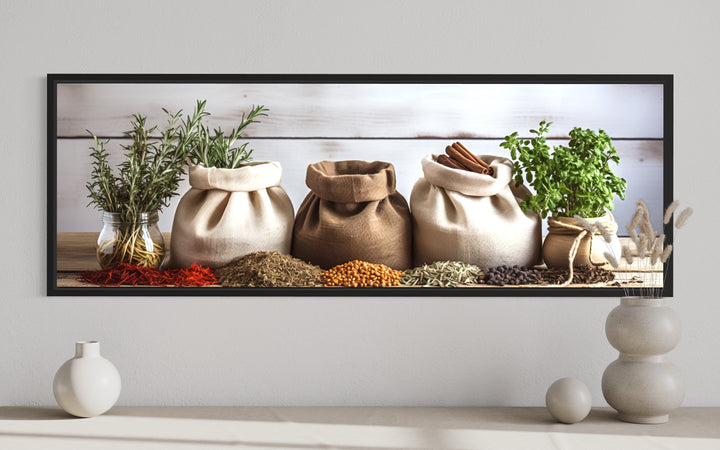 Framed horizontal kitchen wall art featuring rustic bags of spices and fresh herbs on a table.