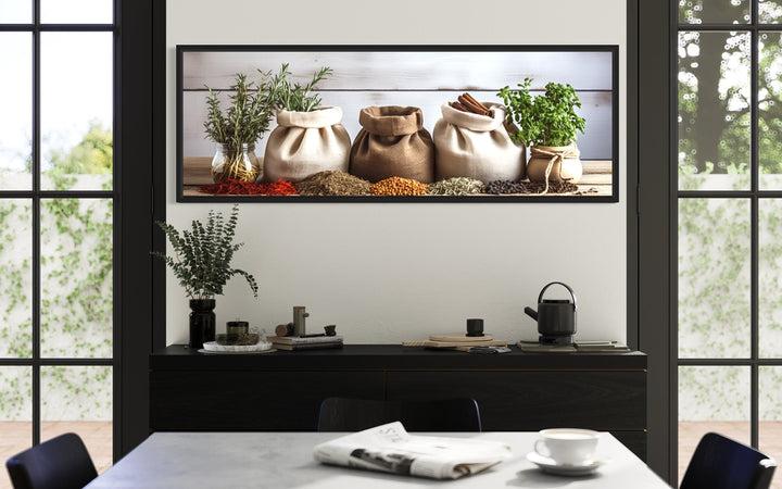 Spices and Herbs long horizontal framed wall art above a black sideboard in a modern kitchen.