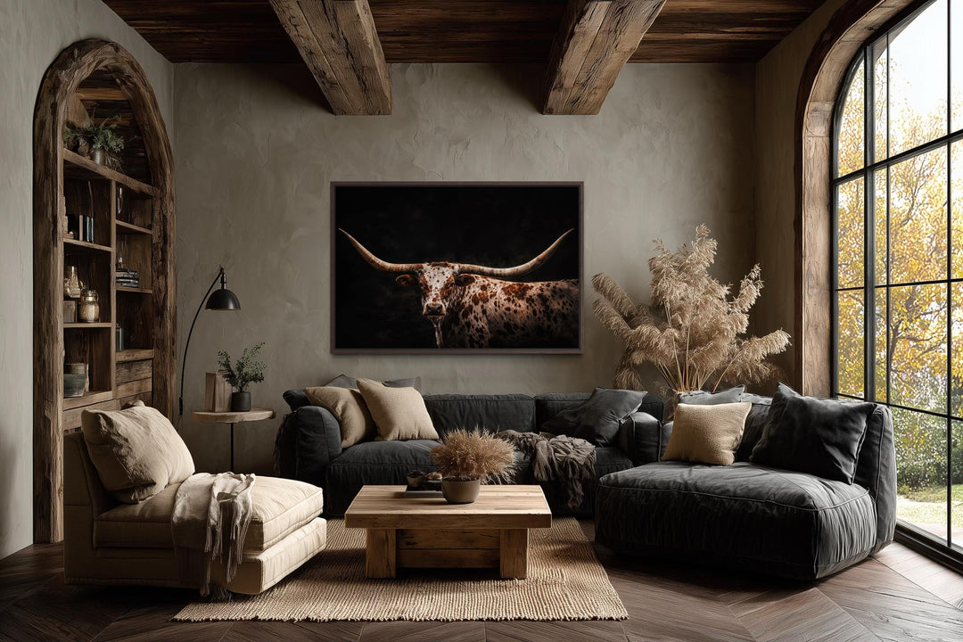 Spotted Texas Longhorn canvas print with a dark background in a rustic living room setting.