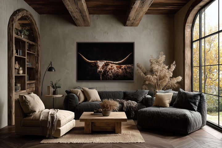 Spotted Texas Longhorn canvas print with a dark background in a rustic living room setting.