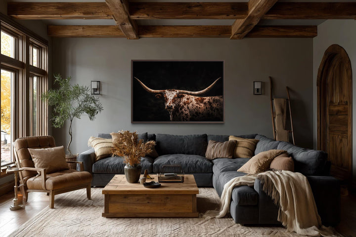 Spotted Texas Longhorn canvas wall art with floating frame above a gray sectional in a rustic room.