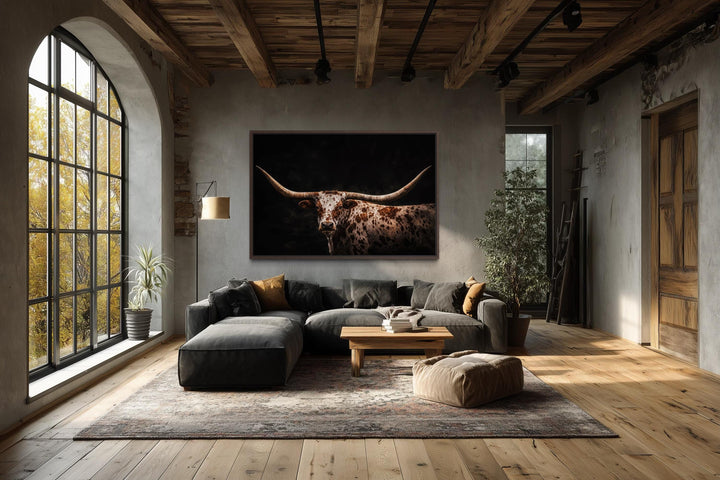 Spotted Texas Longhorn canvas wall art in a rustic living room with a dark dramatic background.