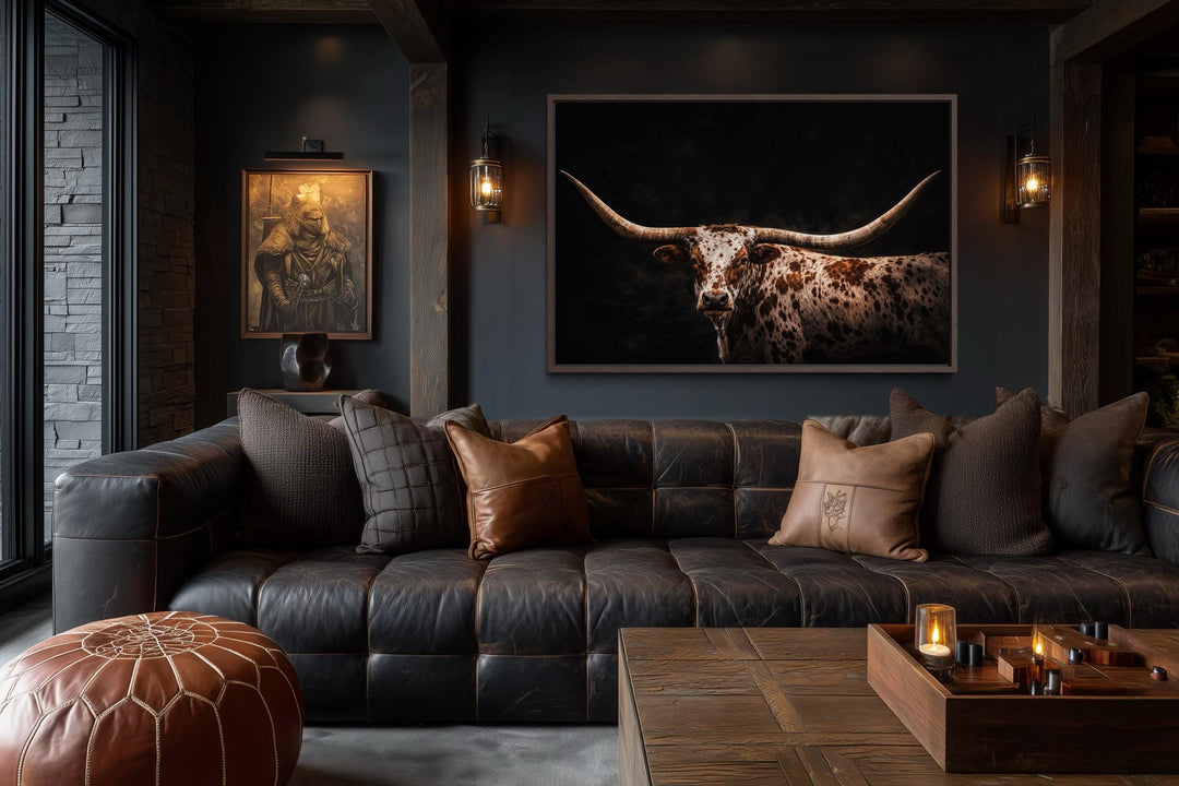 Spotted Texas Longhorn canvas print in a dark rustic living room with leather sofa and wood accents.