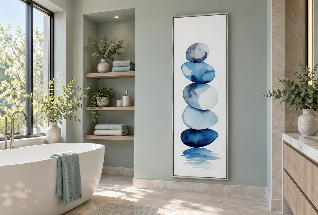 Tall narrow framed canvas art featuring navy blue and white watercolor stacked rocks in a bathroom.