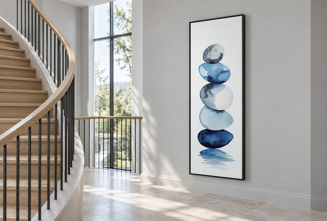Tall narrow framed canvas art of navy blue and white stacked rocks in a modern hallway.
