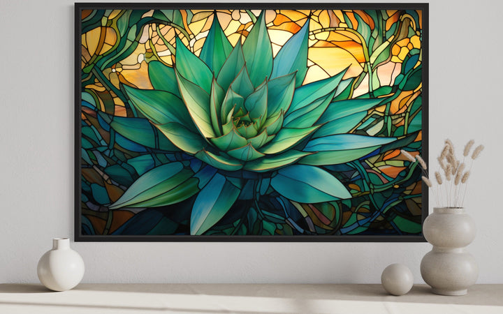 Stained glass style agave plant framed canvas wall art on a white wall above decorative vases.