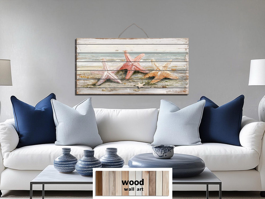 Large horizontal wood wall art featuring three starfish on a beach, hanging above a white sofa.
