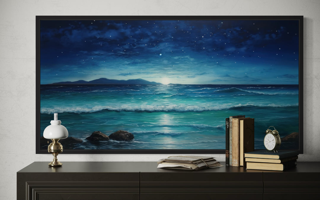Framed panoramic canvas of a starry night over a coastal ocean beach above a dark console table.