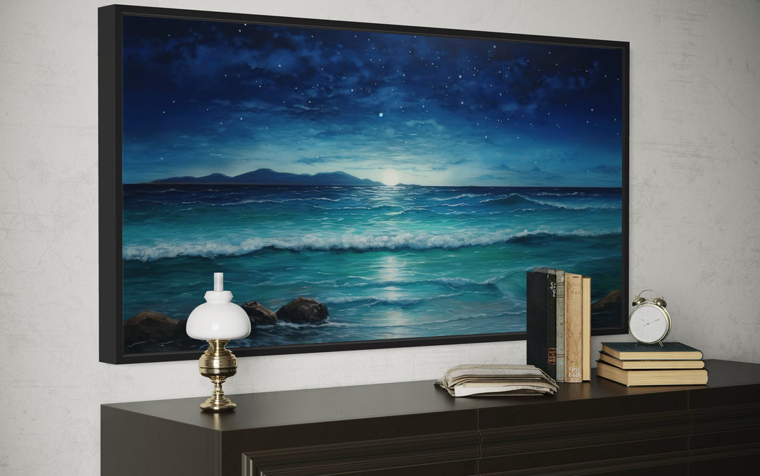 Framed panoramic canvas of a starry night over ocean waves, displayed above a dark wood console.