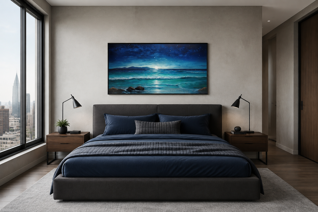 Framed panoramic canvas of a starry night over ocean waves above a dark blue bed in a modern room.