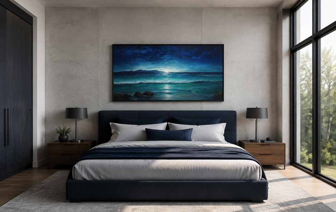 Framed panoramic canvas of a starry night sky over ocean waves above a navy blue bed.