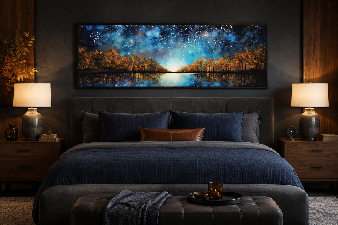 Framed horizontal canvas art of a starry sky and autumn forest over a lake above a dark blue bed.