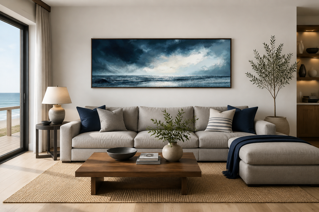 Stormy horizon over the ocean panoramic canvas wall art above a neutral sofa in a living room.