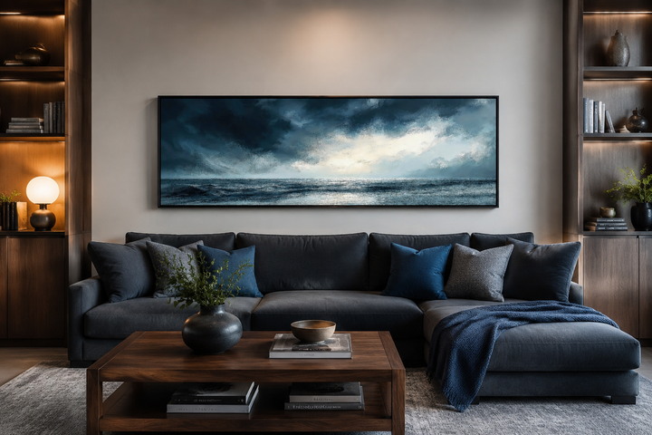 Panoramic canvas wall art of a stormy ocean horizon in dark blue and gray above a modern sofa.