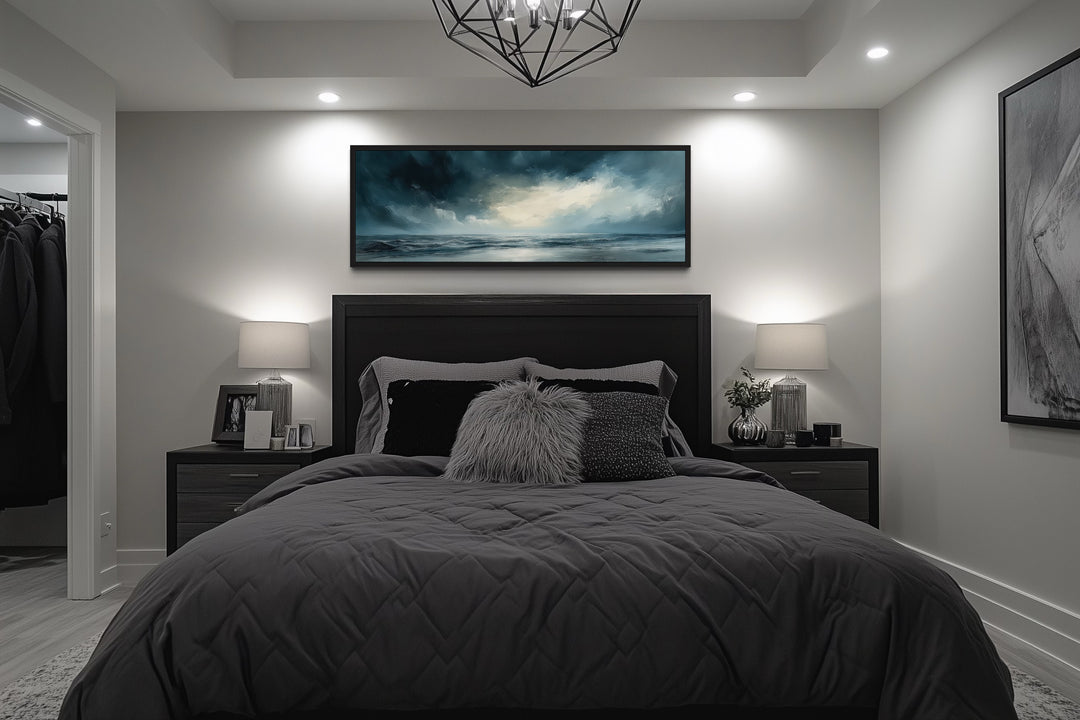 Stormy horizon over the ocean panoramic canvas wall art hanging above a bed in a modern bedroom.