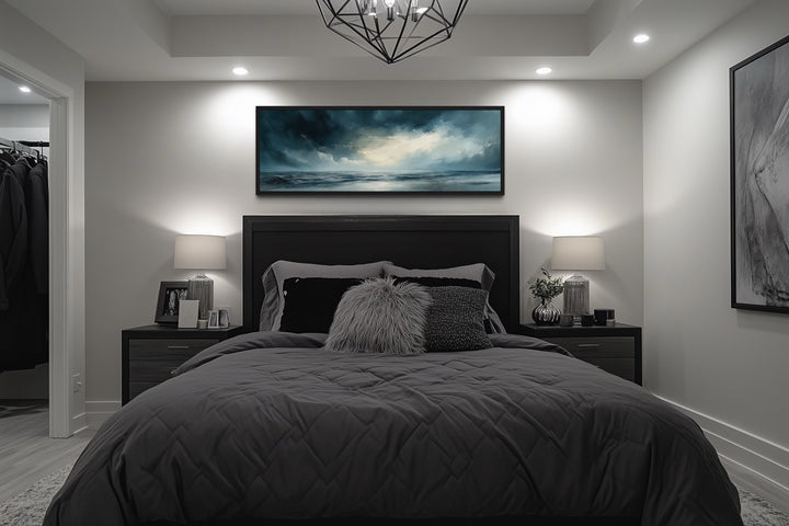 Stormy horizon over the ocean panoramic canvas wall art hanging above a bed in a modern bedroom.