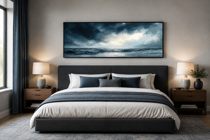 Stormy horizon over the ocean panoramic canvas wall art hanging above a dark gray upholstered bed.