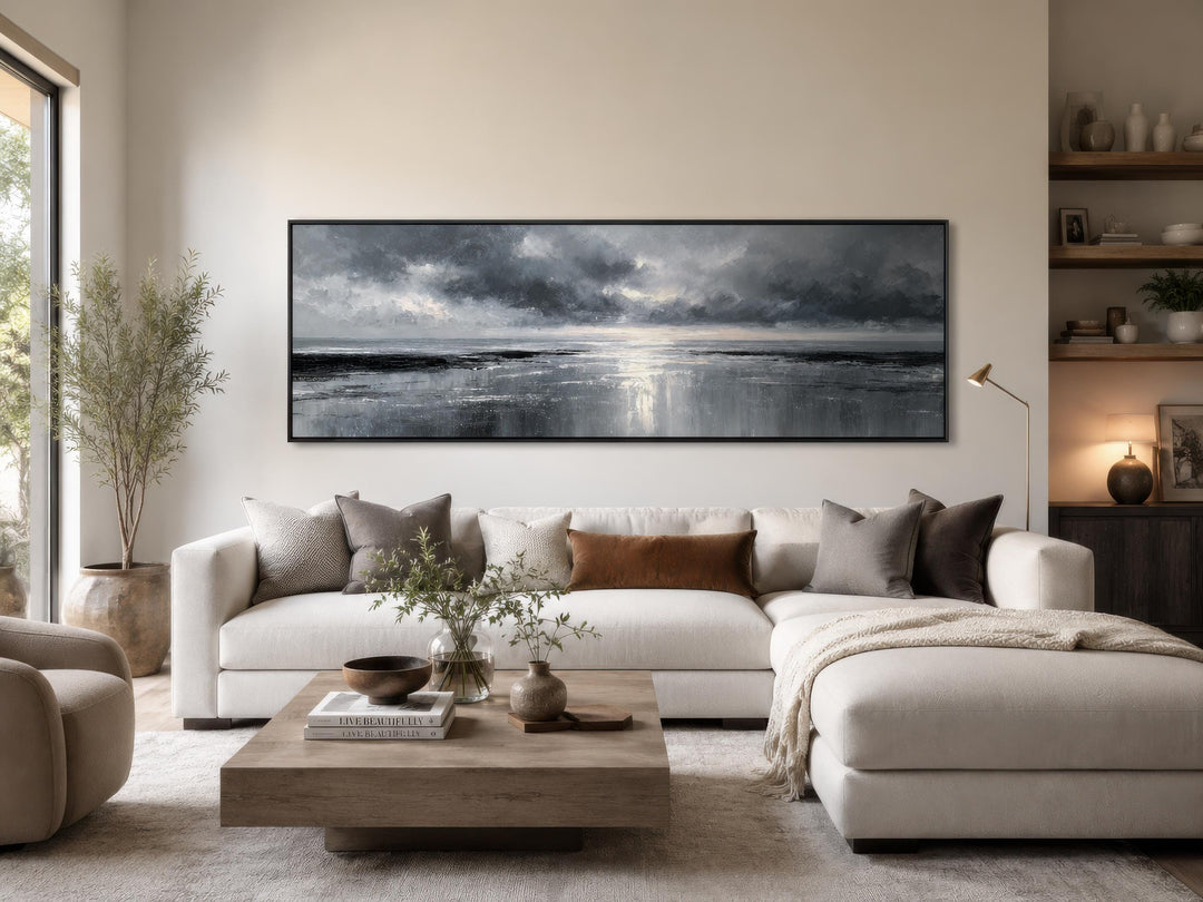 Stormy Ocean wall art, a long horizontal grey and silver canvas above a white sectional sofa.