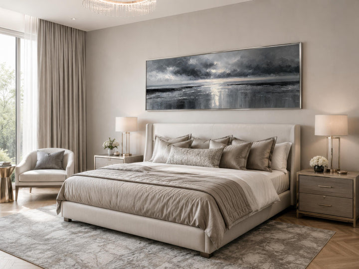 Long horizontal stormy ocean canvas wall art in grey and silver above a bed in a neutral bedroom.