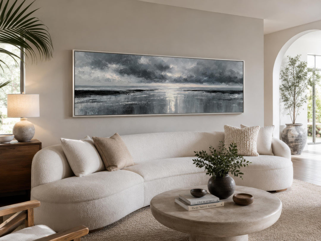 Stormy Ocean long horizontal grey and silver canvas wall art above a curved white sofa.