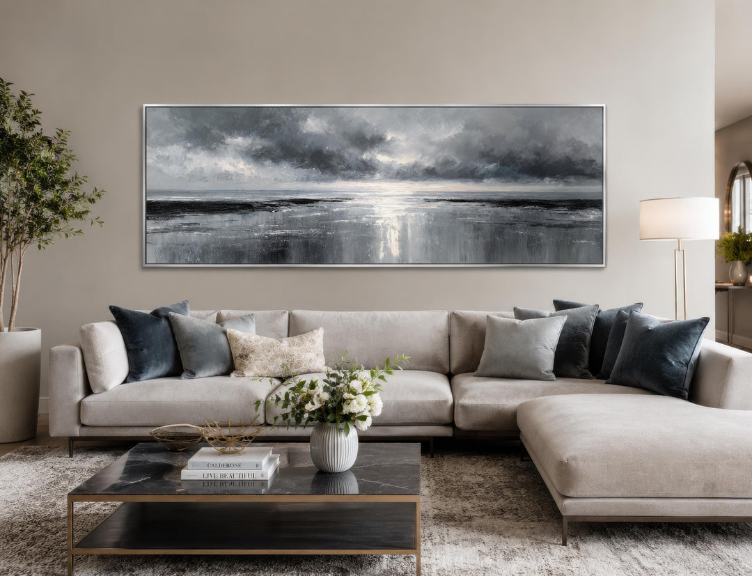 Stormy Ocean wall art, a long horizontal grey and silver canvas painting above a modern sofa.