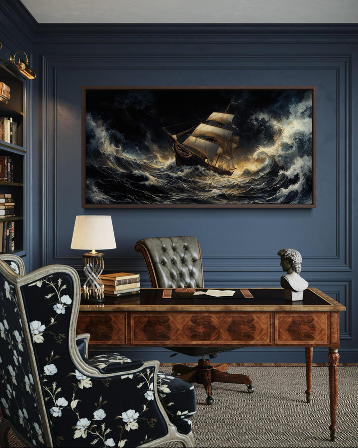 A framed canvas print of a sailing ship navigating a stormy ocean on a dark blue paneled wall.