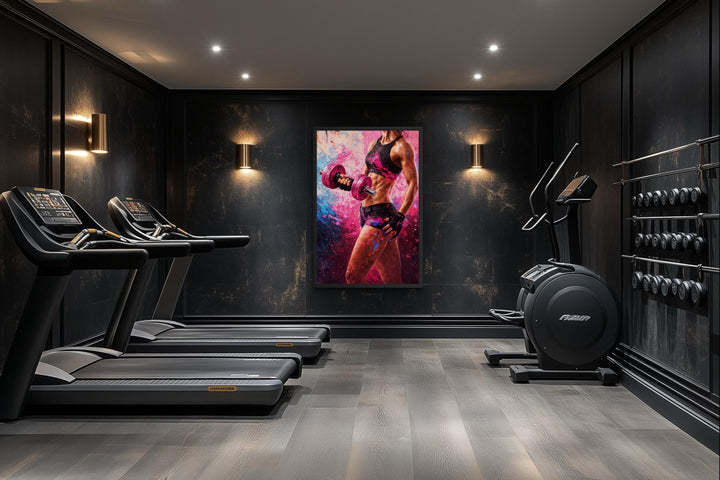 A motivational canvas print of a strong woman lifting a dumbbell in a modern, dark home gym.