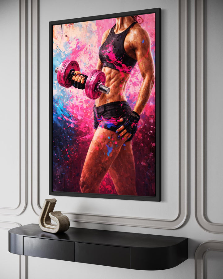 A framed canvas print of a muscular woman lifting a pink dumbbell with vibrant paint splatter effects.