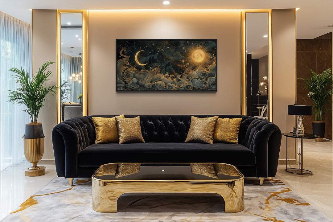 Framed black and gold celestial canvas art with sun and moon above a black sofa in a living room.