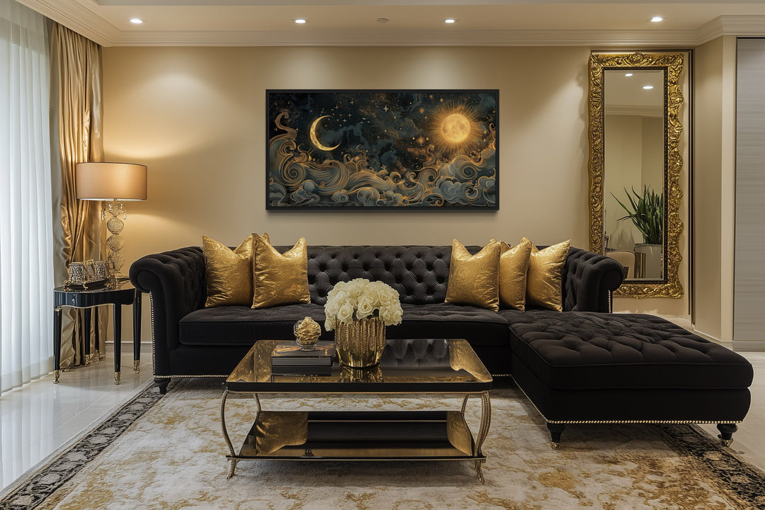 Framed celestial wall art of a gold sun and moon with swirling clouds above a black velvet sofa.