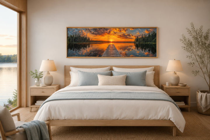 Sunrise over lake and fishing pier long horizontal canvas wall art hanging above a bed.