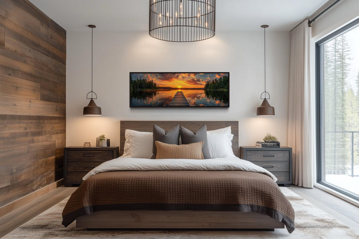 Sunrise over lake and fishing pier long horizontal canvas wall art hanging above a bed.