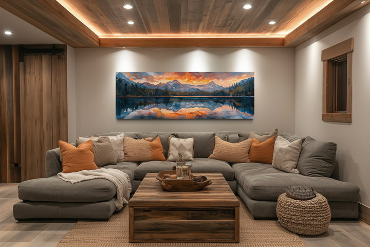 Panoramic sunset over mountain lake canvas wall art hanging above a large grey sectional sofa.