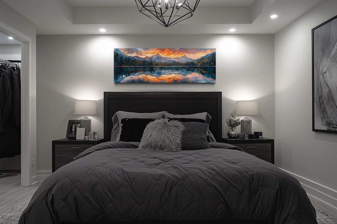 Panoramic framed canvas wall art of a sunset over a mountain lake hanging above a bed.
