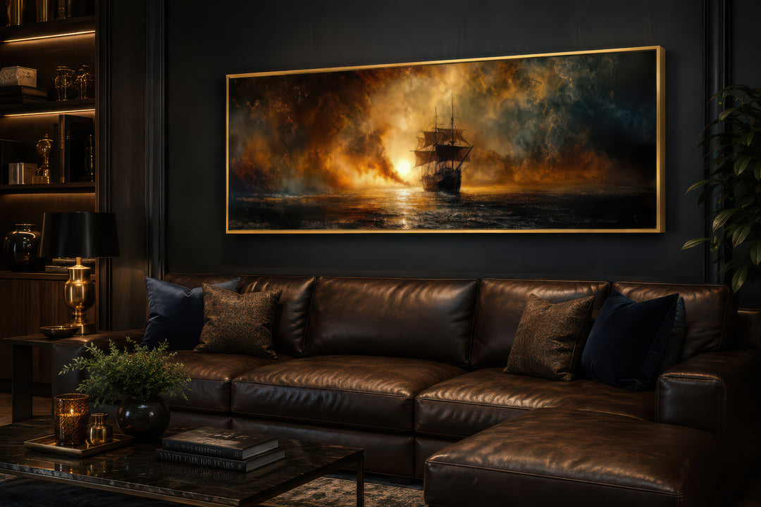 Sunset sailing ship horizontal canvas wall art in a gold frame above a brown leather sofa.