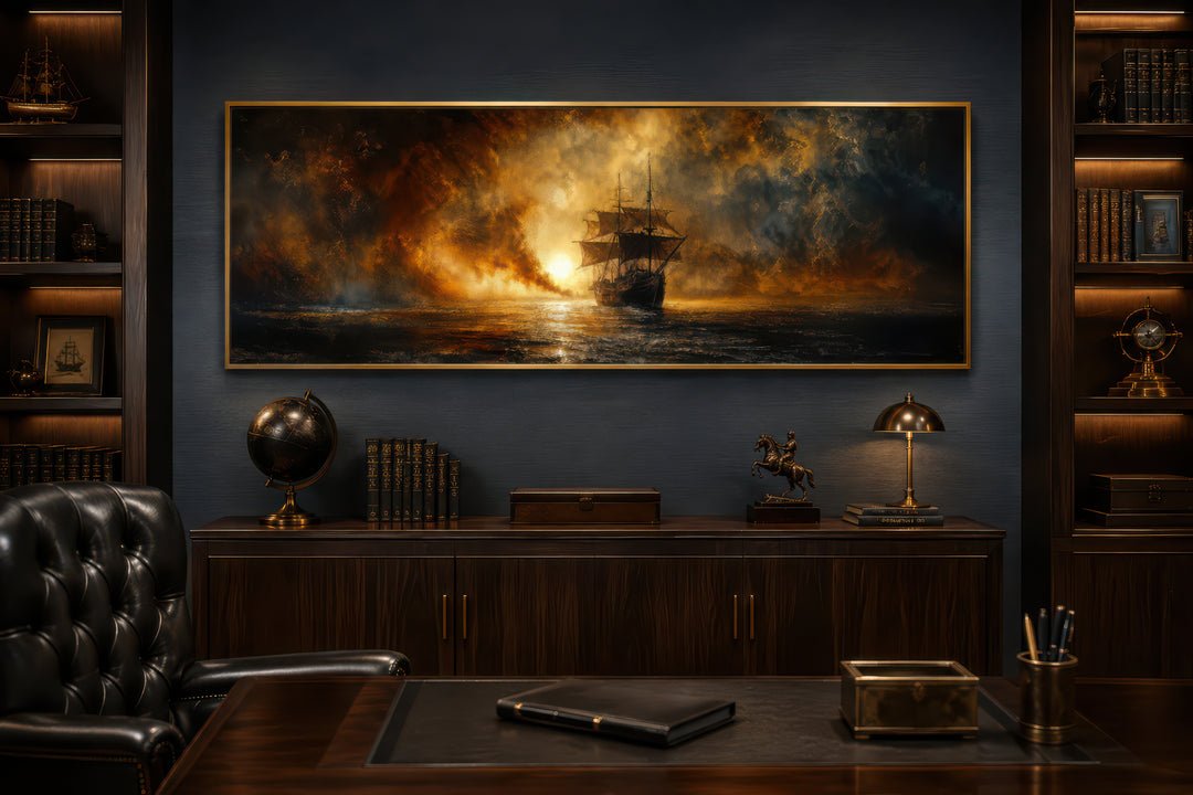 Sunset sailing ship canvas wall art in a gold frame above a dark wood desk in a home office.