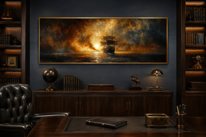 Sunset sailing ship canvas wall art in a gold frame above a dark wood desk in a home office.