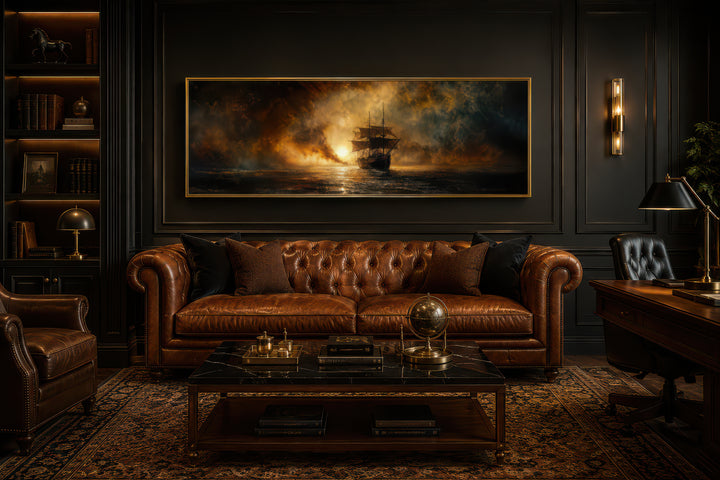 Sunset sailing ship horizontal canvas wall art in a gold frame above a brown leather sofa.