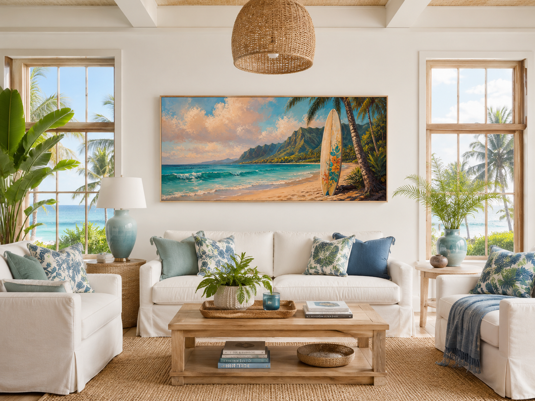 Framed canvas wall art of a surfboard on a Hawaiian beach at sunset above a white sofa.