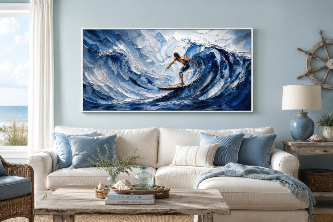 A wide horizontal canvas print of a surfer riding a large blue wave in a coastal living room.