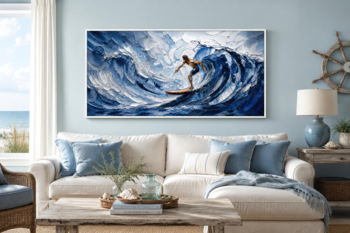A wide horizontal canvas print of a surfer riding a large blue wave in a coastal living room.