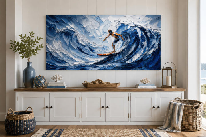 A large canvas print of a surfer on a blue wave hangs above a white coastal-style sideboard.
